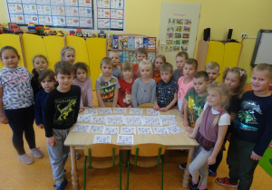 Grupa dzieci stoi wokół stolika, na którym ułożone są kartki z ułożonym sudoku.